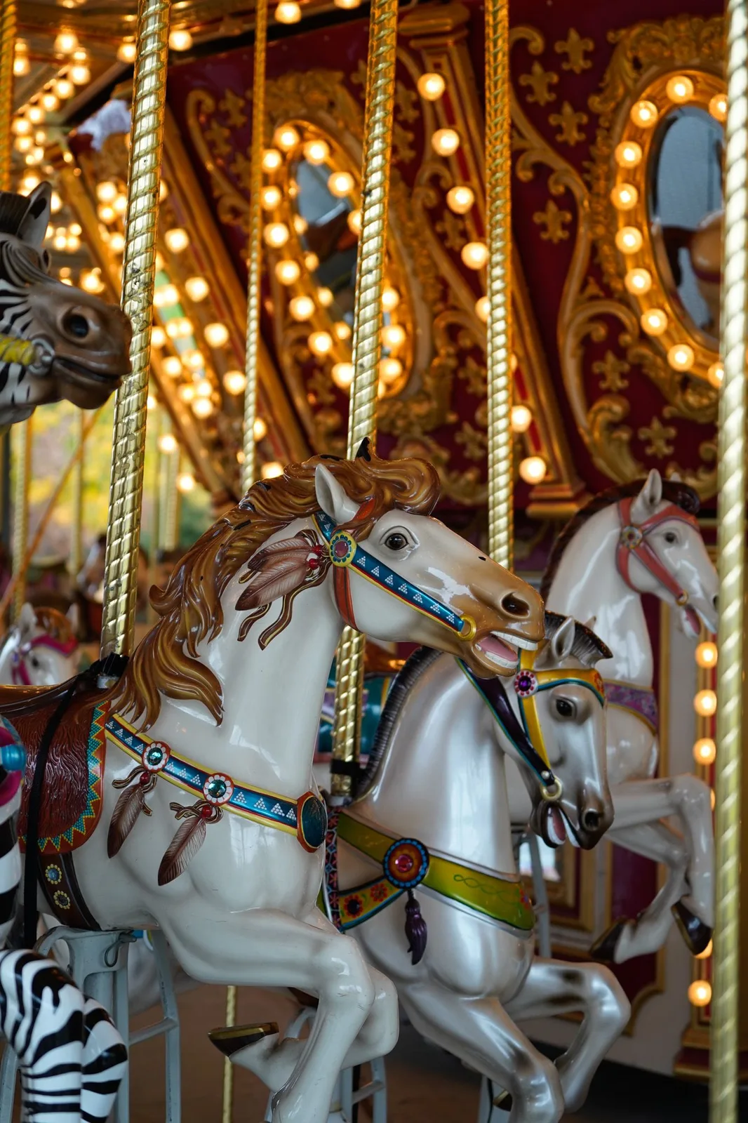 Vintage carousel horses lit by warm bulbs at a fairground — Maximus Visions wedding photography, New Jersey & New York City