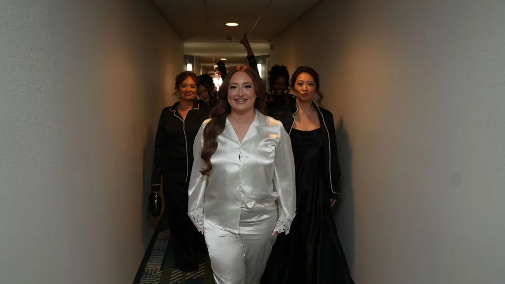 Becky in a white silk set leads her bridesmaids down the hallway, candid wedding-morning moment, New Jersey