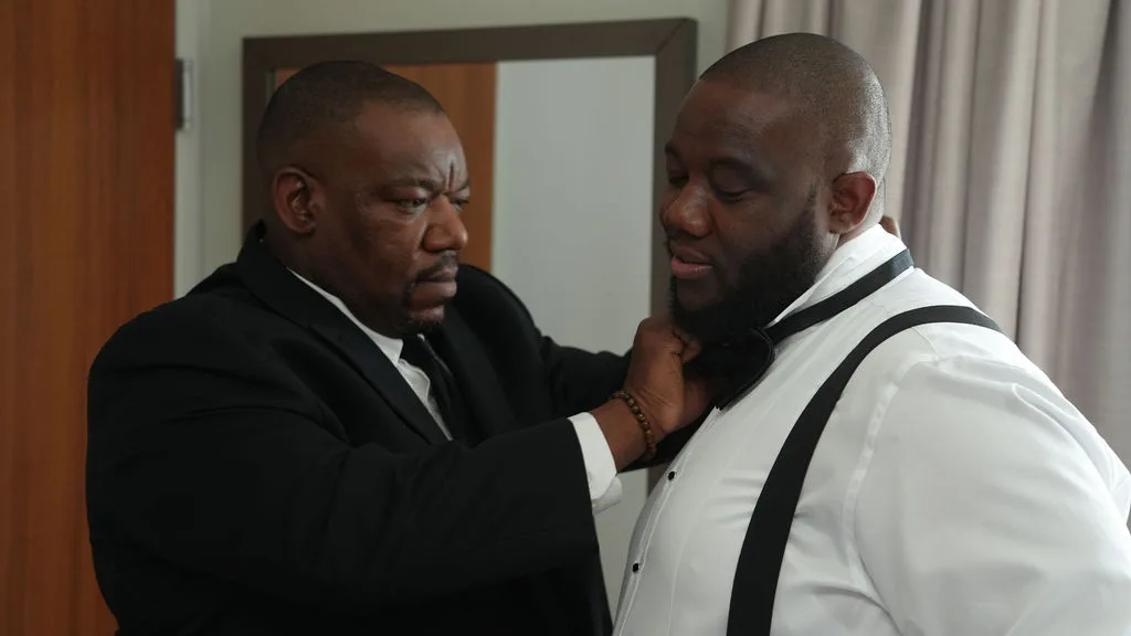 Helping hands set the groom's collar before the tuxedo goes on — documentary wedding photography, New Jersey