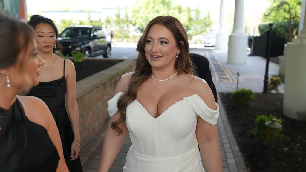 Becky arrives in her off-the-shoulder white gown and pearls, bridesmaids at her side — moments before the ceremony, New Jersey