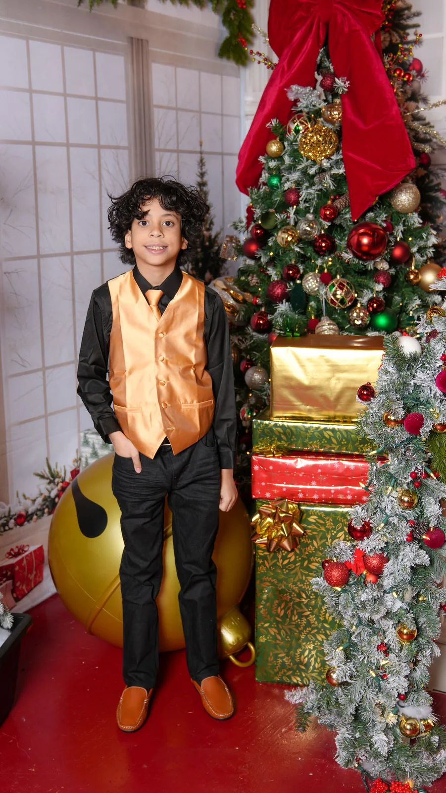 The younger Marlin son in his gold vest and boots in front of stacked presents on the staircase set — Christmas session, Maximus Visions, New Jersey