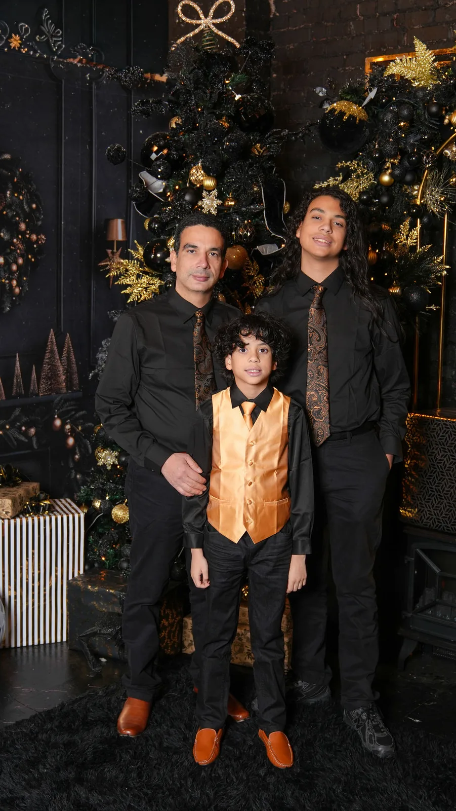 Dad and his two boys in black and gold before the darkened Christmas tree — holiday family session by Maximus Visions, New Jersey