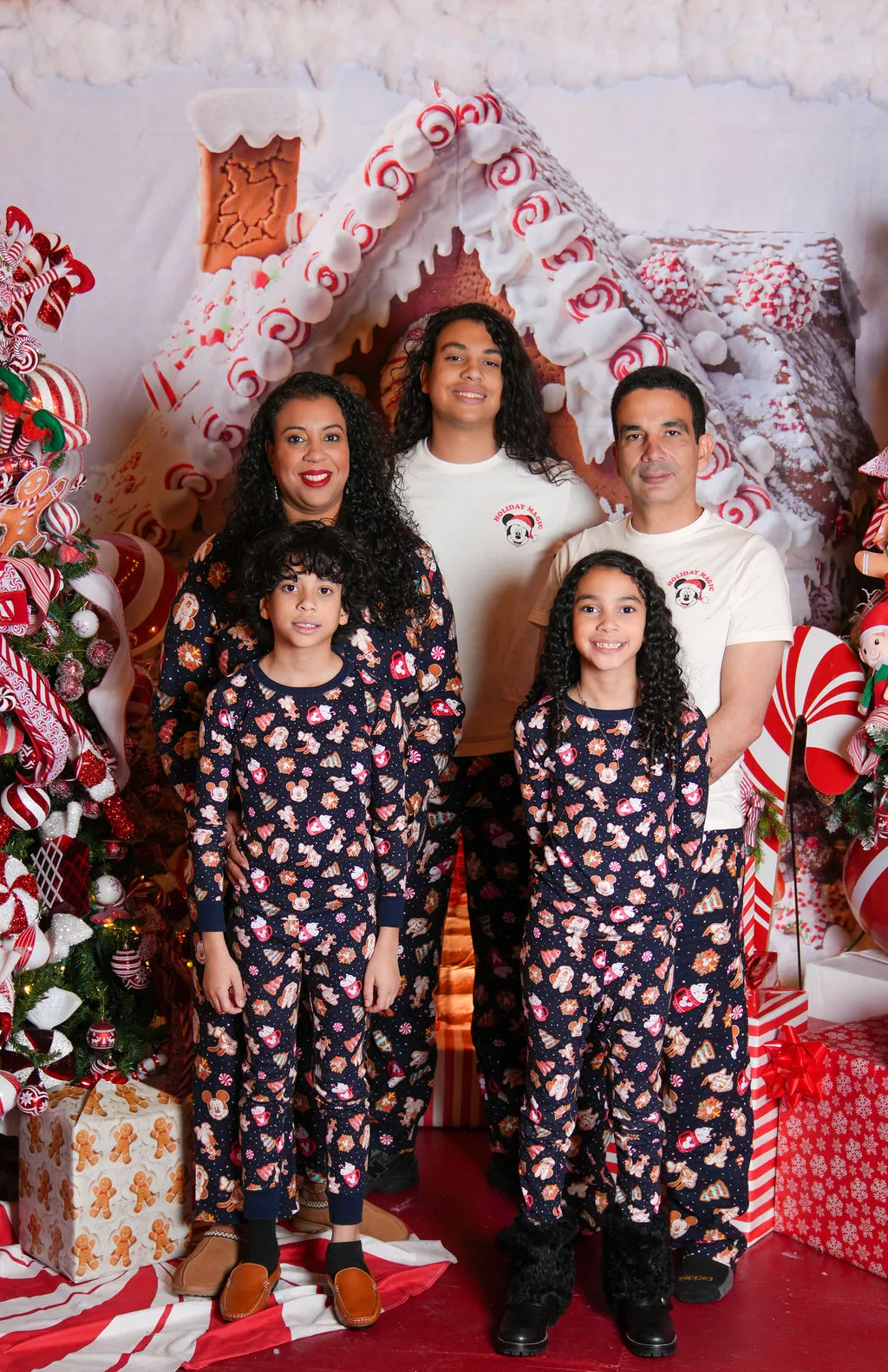 Family in matching holiday pajamas in front of a giant gingerbread-house set — festive holiday portrait scene by Maximus Visions, New Jersey & New York City