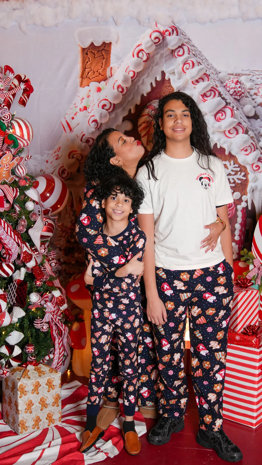 Mom plants a kiss on her boys in matching gingerbread pajamas at the candy-cane set — candid holiday moment, Maximus Visions, New Jersey