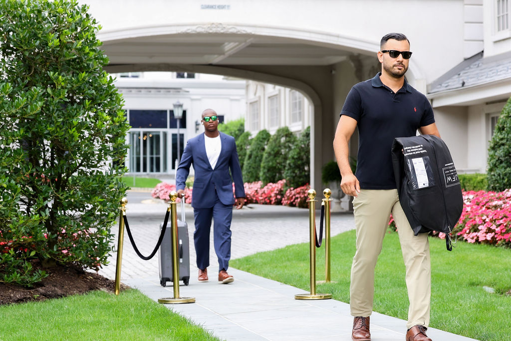 Groomsman walks the estate path while groom approaches in navy suit at Park Chateau, NJ wedding