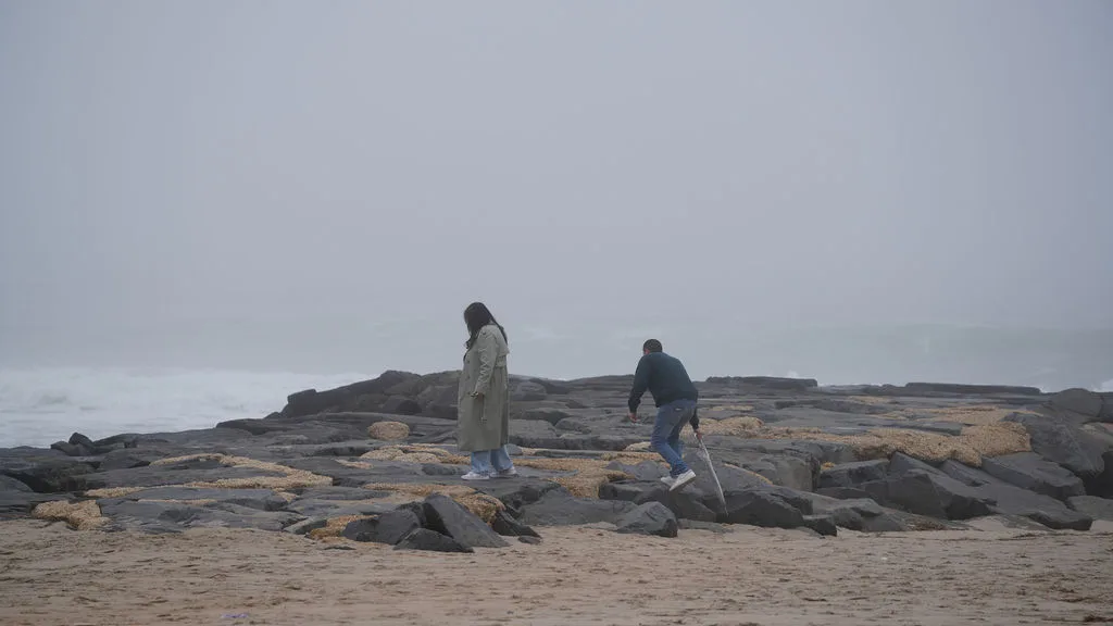 He steps up the wet jetty stones, umbrella in hand, leading the way — proposal session by Maximus Visions, NJ