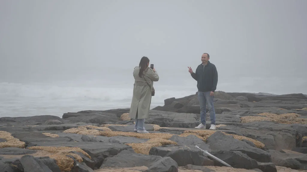 She photographs him on the rocks as he flashes a peace sign — the decoy moments before the surprise proposal, New Jersey