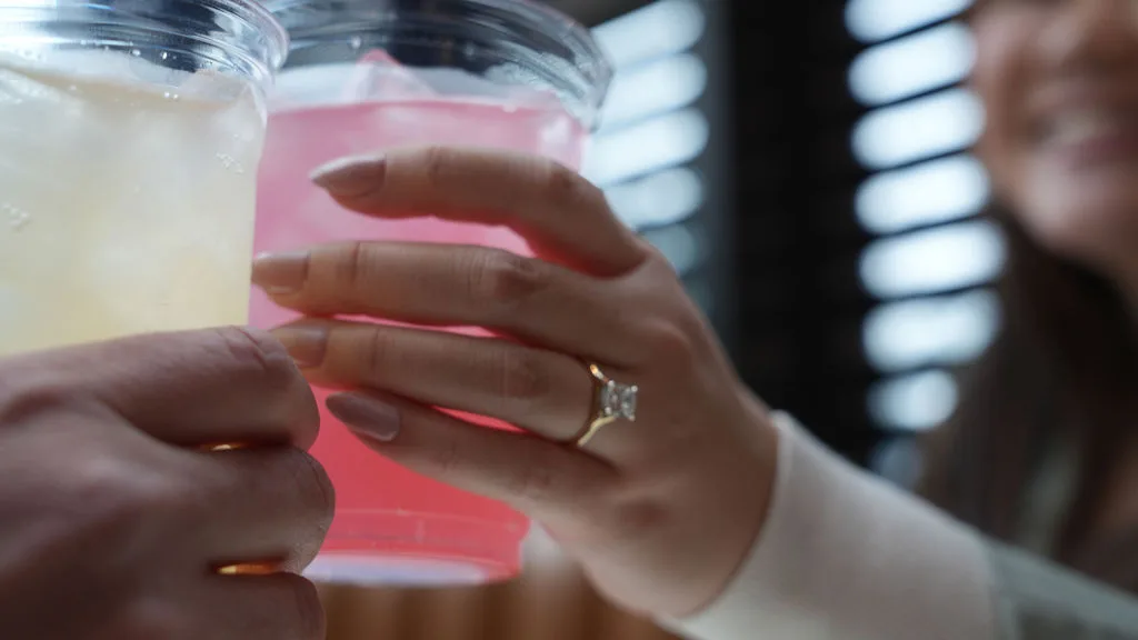 Cheers — her hand with the engagement ring wrapped around a celebratory drink, New Jersey